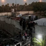 Protesters climb a fence as they gather near the Swedish embassy in Baghdad hours after the embassy was stormed. [Photo/Courtesy]