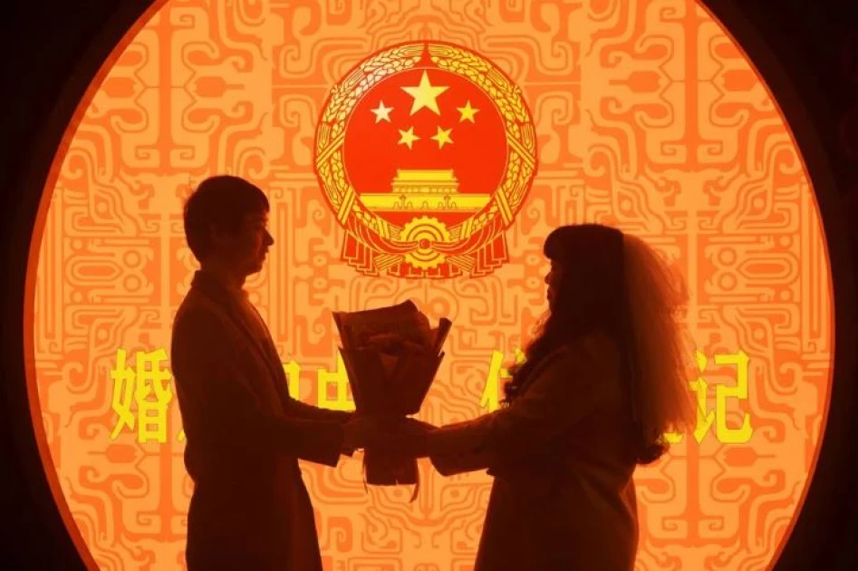 A newly wed couple pose for pictures on Valentine's Day at a marriage registration office in Hangzhou, Zhejiang province, China February 14, 2023. [China Daily via REUTERS/File Photo]