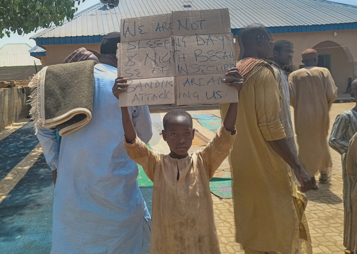 FILE PHOTO: A boy holds a sign to protest against, what a teacher, local councilor and parents said, the kidnapping of hundreds school pupils by gunmen after the Friday prayer, in Kaduna