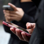 FILE PHOTO: Teenagers look at their mobile phone screens in Paris