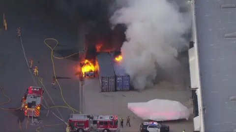Firefighters work at the scene of a crashed news helicopter in Los Angeles after three people were confirmed dead.